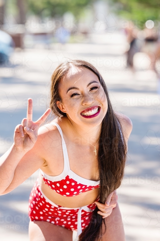 happy asian woman in bikini making peace sign - Australian Stock Image