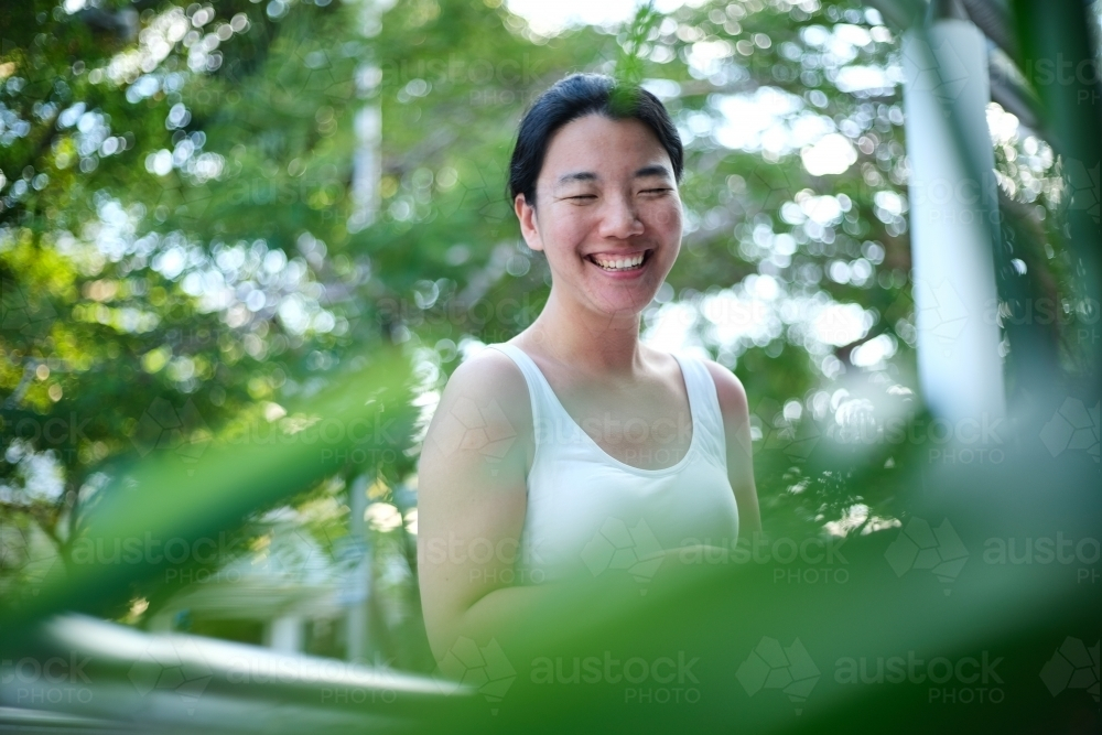 Image of Happy Asian woman standing outside on walkway among greenery ...