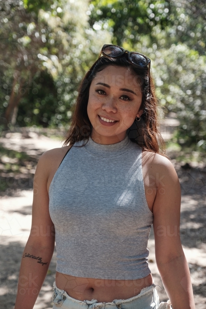 Happy Asian young adult woman in the park - Australian Stock Image