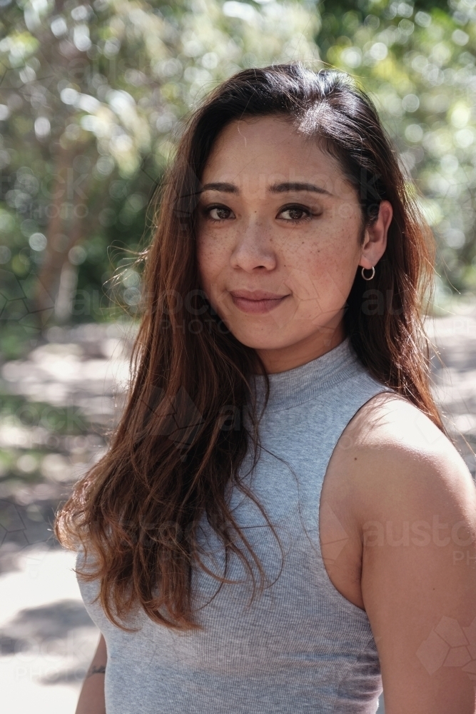 Happy Asian young adult woman in the park - Australian Stock Image