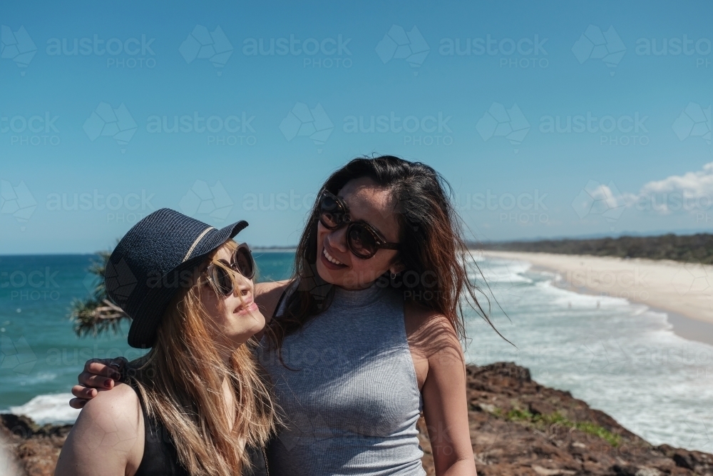 Happy Asian young adult women on coastline - Australian Stock Image