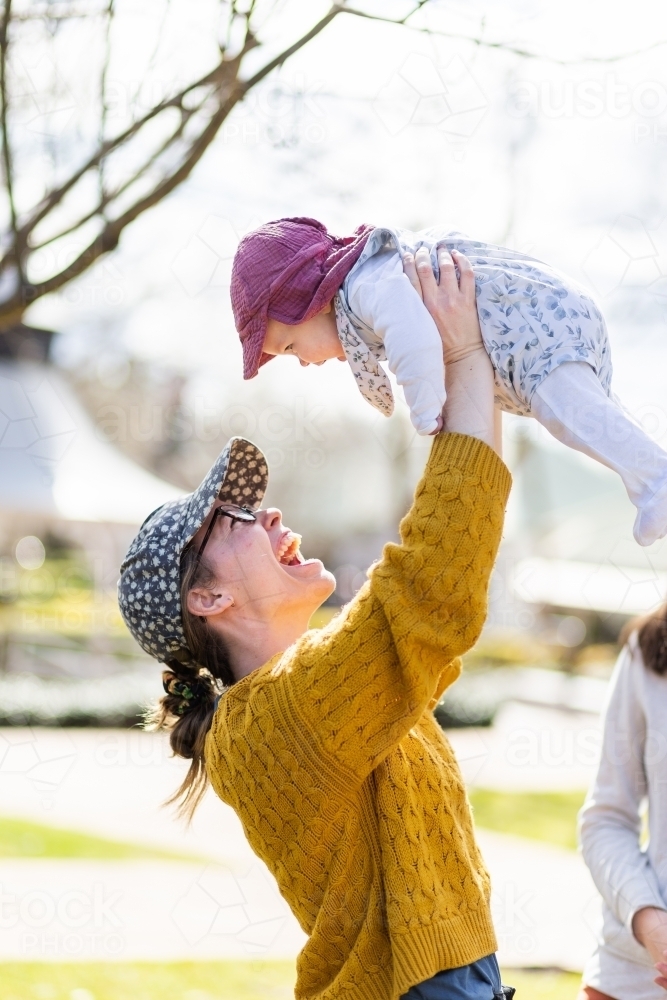 Happy aunty in her twenties playing with baby niece outside - Australian Stock Image