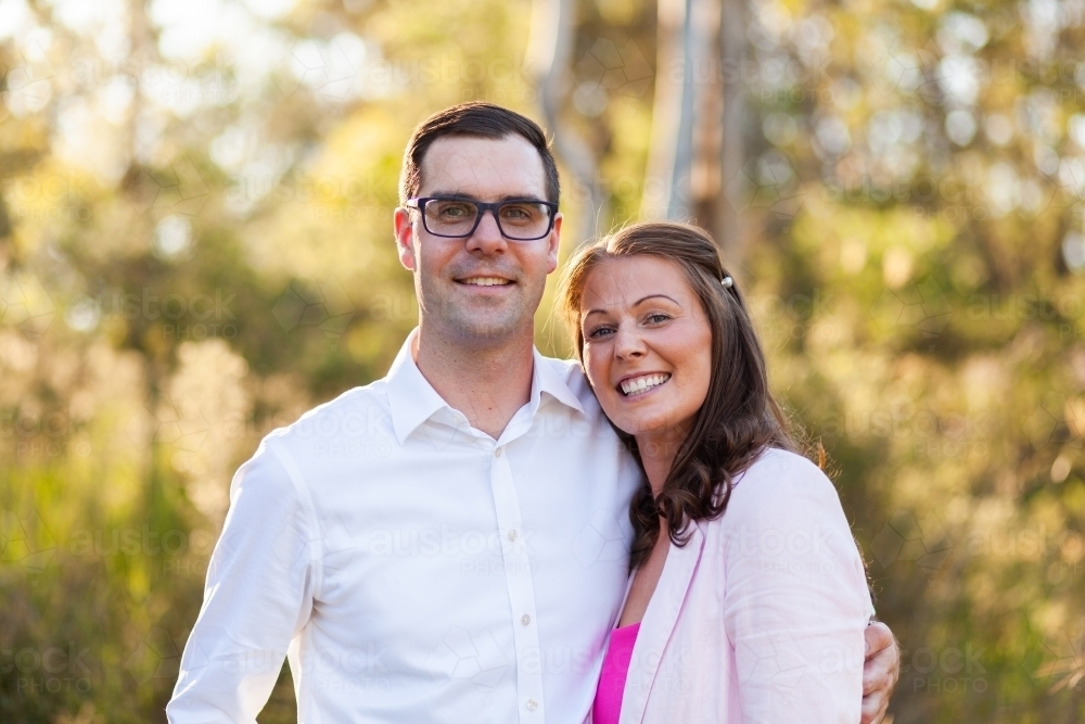 Happy aussie couple standing together outside at park with natural backdrop - Australian Stock Image