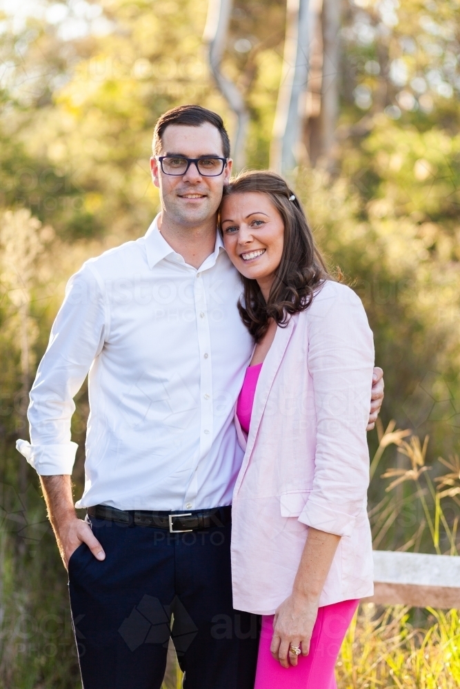 Happy aussie couple standing together outside at park with natural backdrop - Australian Stock Image