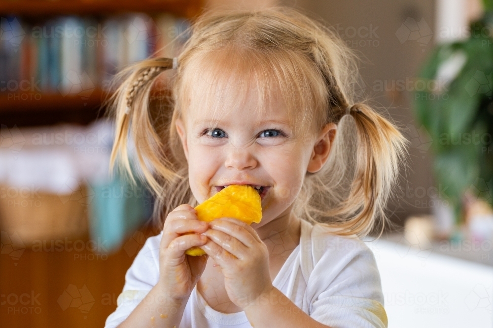 Happy Aussie kid eating mango seed getting sticky - Australian Stock Image