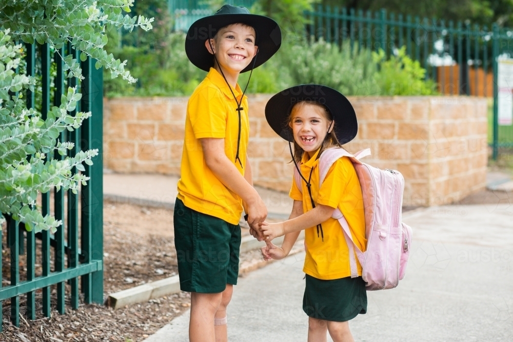 Happy Aussie school girl and boy in uniform outside school - Australian Stock Image