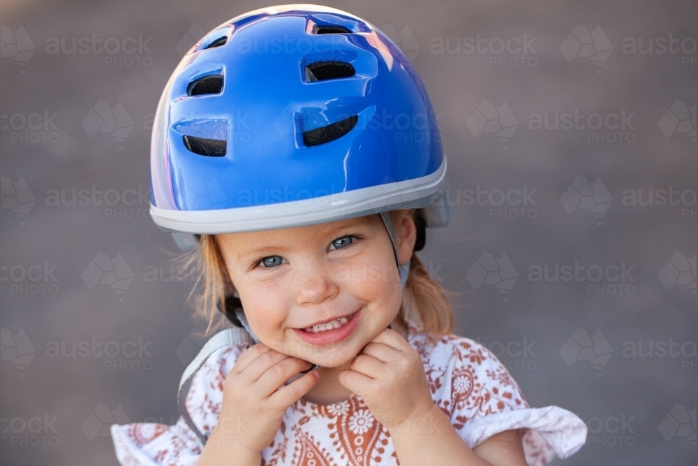 Happy Aussie toddler wearing bike helmet for safety while riding - Australian Stock Image
