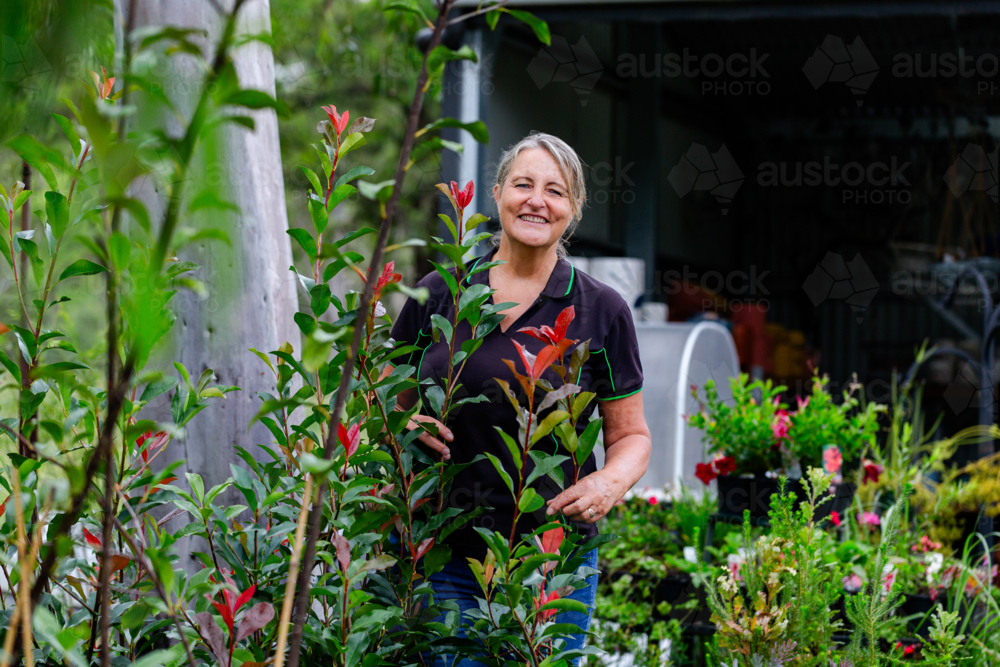 Happy Australian female horticulturalist smiling portrait in nursery garden - Australian Stock Image