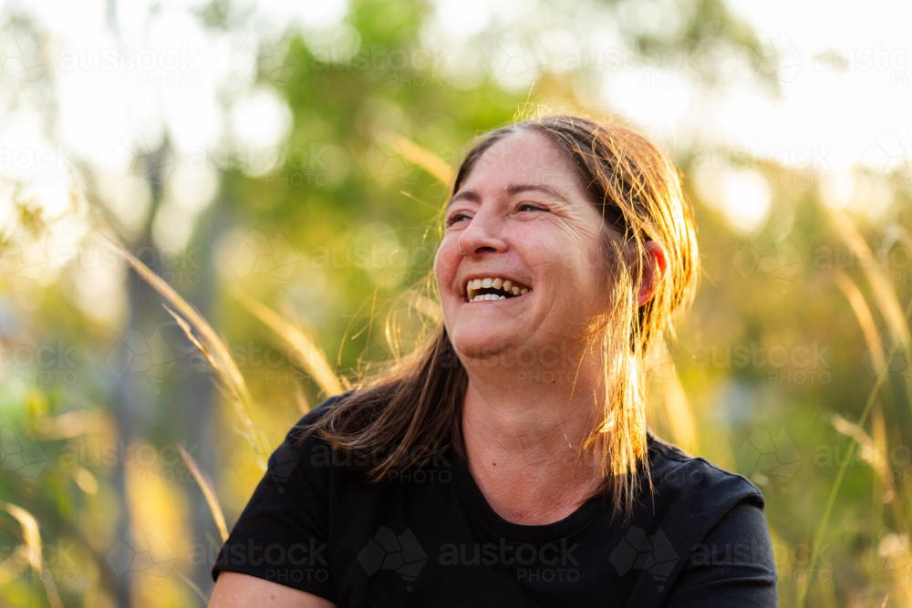 Happy Australian woman laughing in golden sunset light outdoors - Australian Stock Image