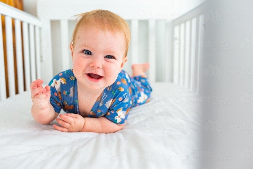 Image of Happy baby crawling in cot bed Austockphoto