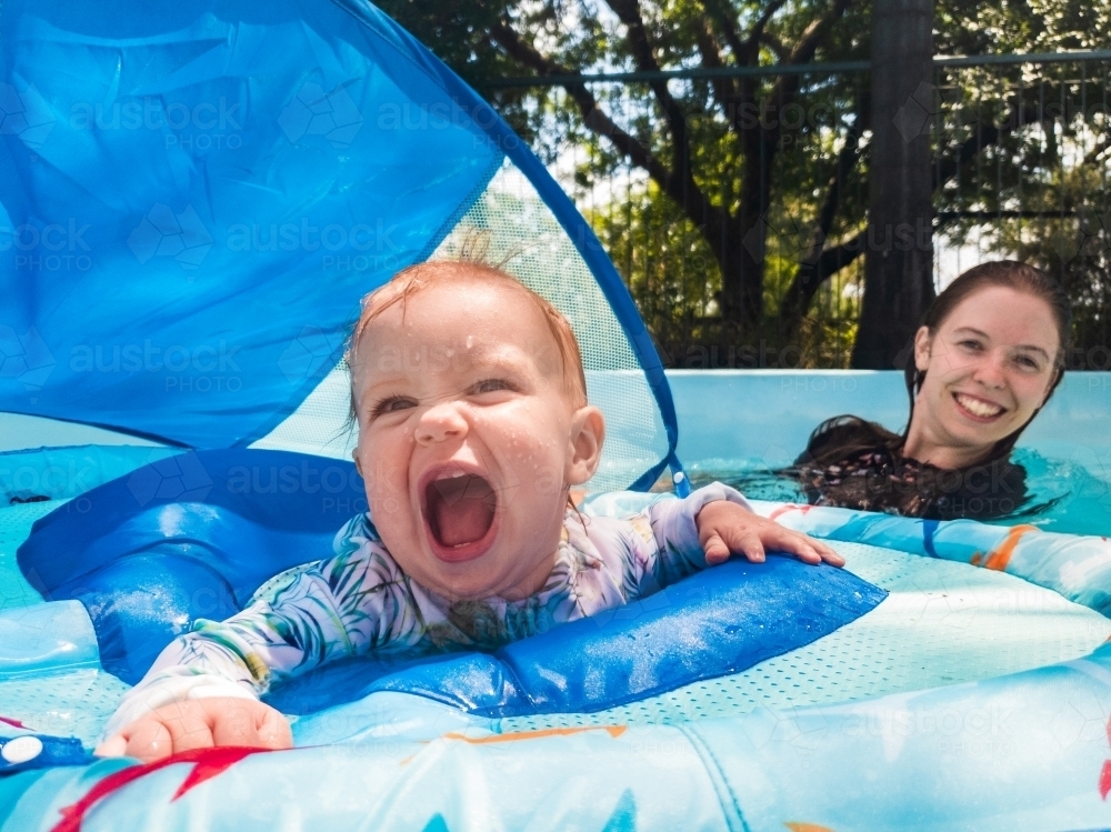 Image of happy baby laughing in flotation device in backyard pool