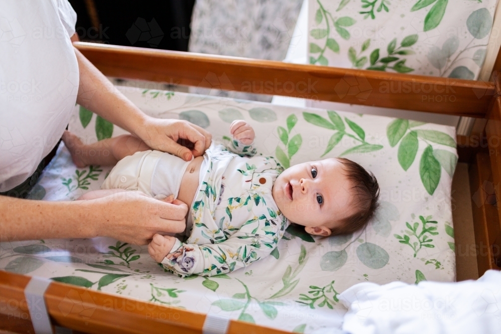 Happy baby on change table getting nappy changed ready for the day - Australian Stock Image