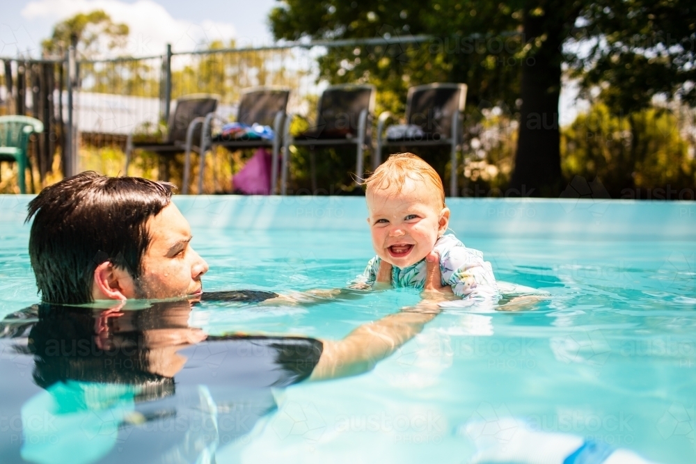 Baby Pool Time Image of happy baby swimming in backyard pool with dad in summer ...