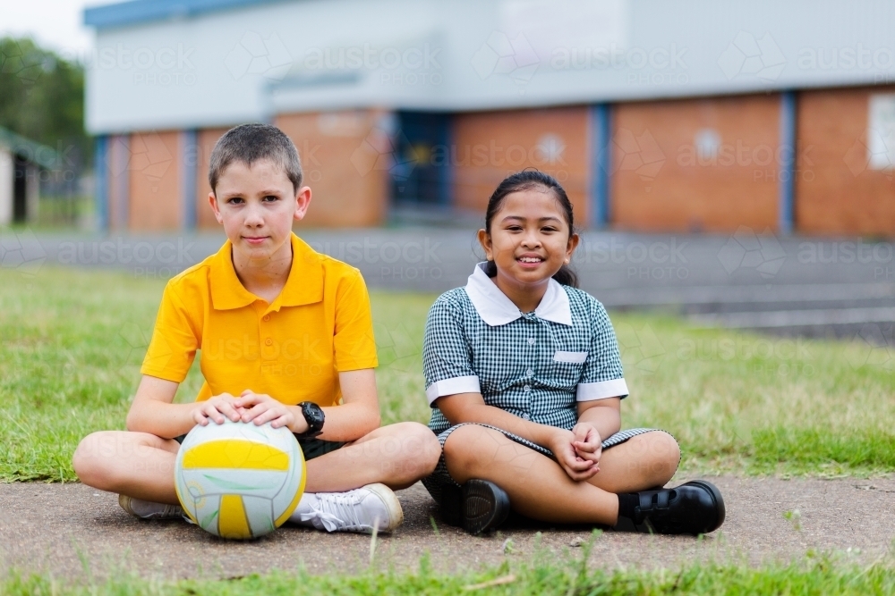 Happy boy and girl at school playing a ball game in a circle during pe - Australian Stock Image