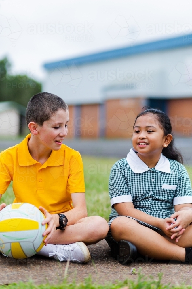 Happy boy and girl at school playing a ball game in a circle during pe - Australian Stock Image
