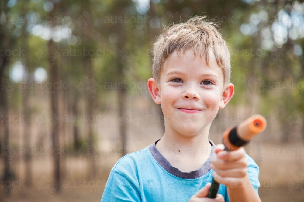Happy boy holding a garden hose - Australian Stock Image