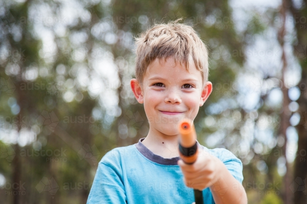 Happy boy looking at camera holding hose - Australian Stock Image
