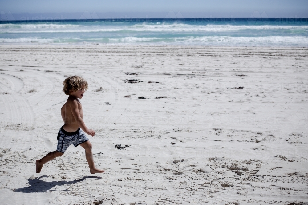 Happy boy running at beach - Australian Stock Image