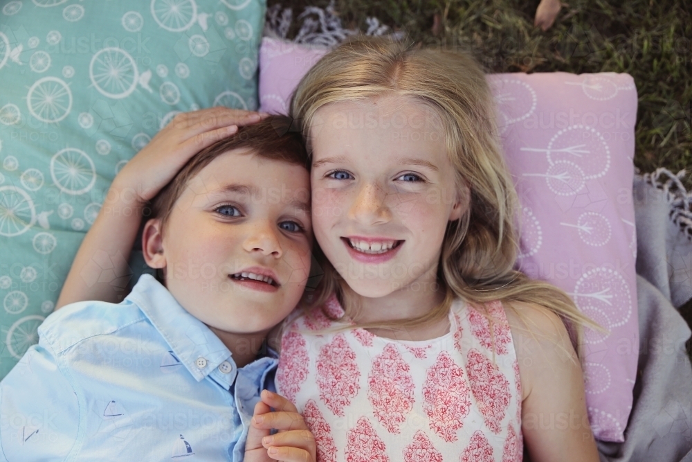 Happy brother and big sister lying in the park - Australian Stock Image