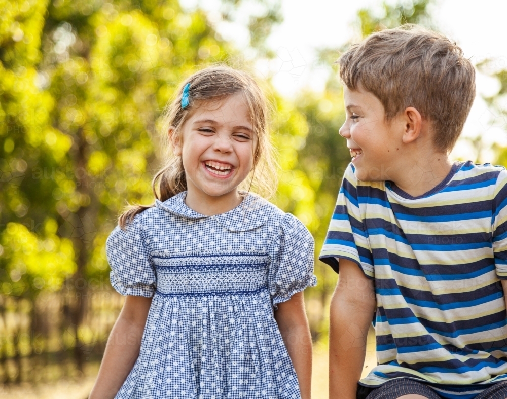 Happy brother and sister laughing together outside - Australian Stock Image