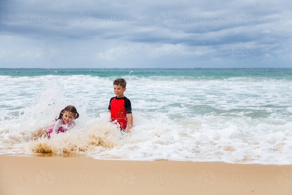 Happy brother and sister playing together on the beach - Australian Stock Image
