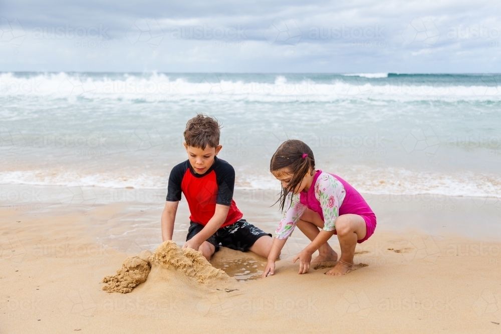 Happy brother and sister playing together on the beach - Australian Stock Image