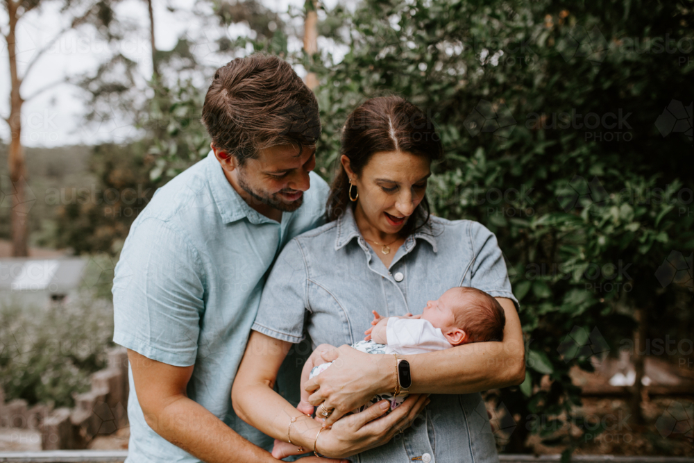 Happy Caucasian parents holding their infant outdoors - Australian Stock Image