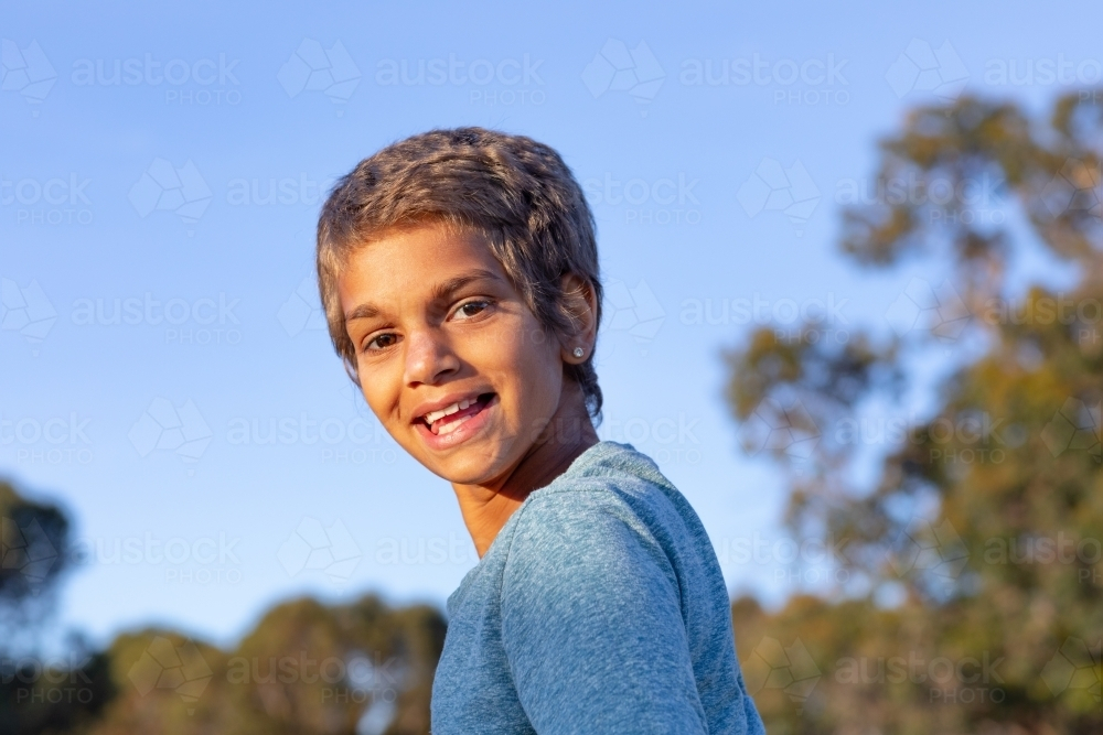 happy child looking over her shoulder outdoors - Australian Stock Image
