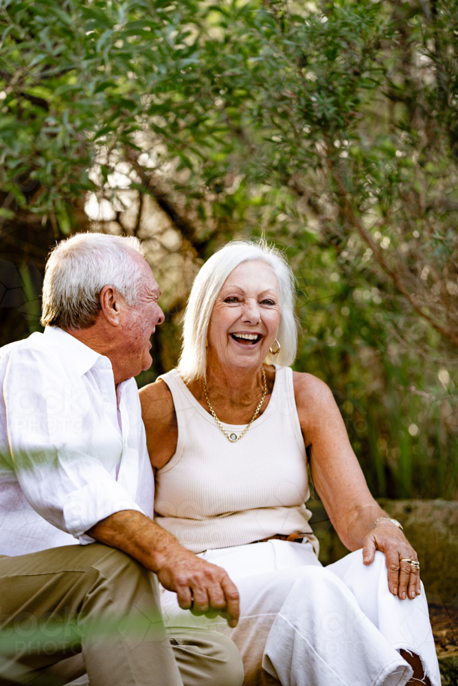 Happy couple laughing while sitting on stairs outdoors - Australian Stock Image