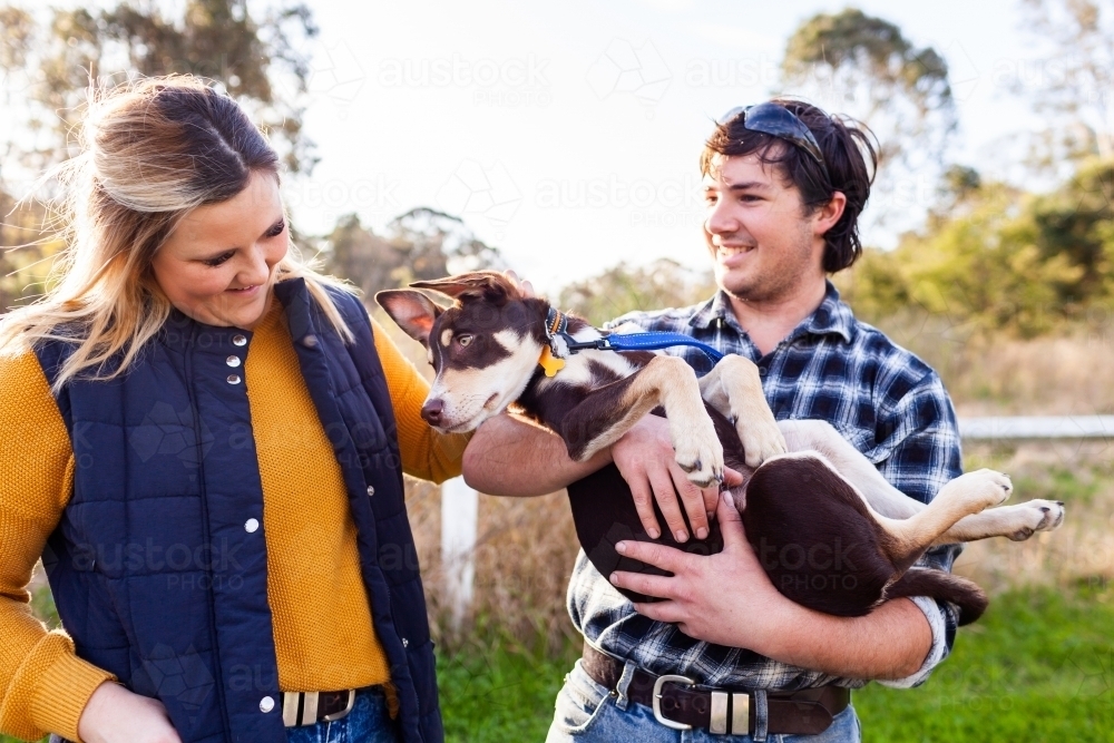 Happy couple outside with pet Australian Kelpie puppy dog - Australian Stock Image