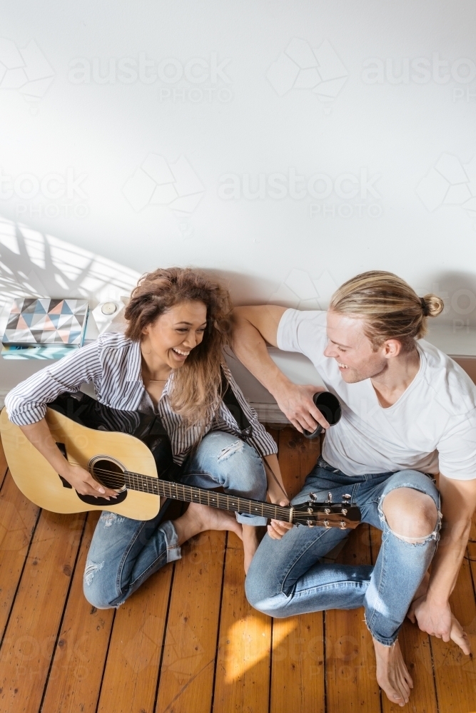 Happy couple playing guitar with clear space above - Australian Stock Image