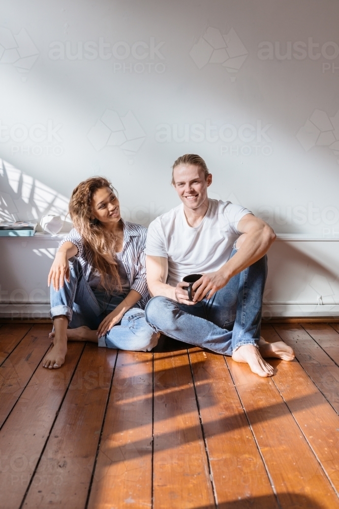 Happy couple sitting in their new apartment having coffee - Australian Stock Image