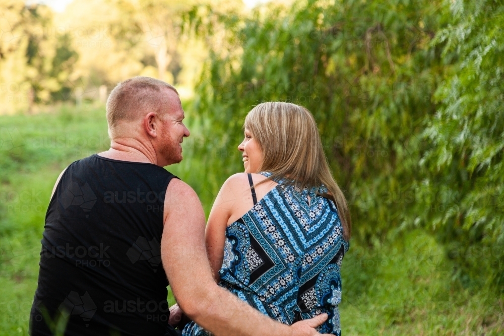 Happy couple sitting together outside in nature - Australian Stock Image