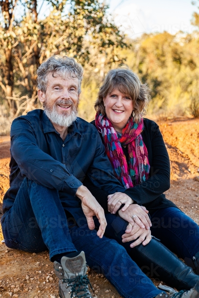 happy couple sitting together outside on bushwalk - Australian Stock Image