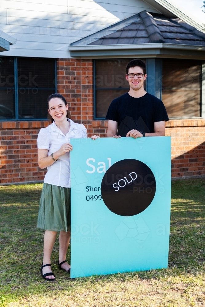 Image of Happy couple standing in front of house with sold sign - first ...