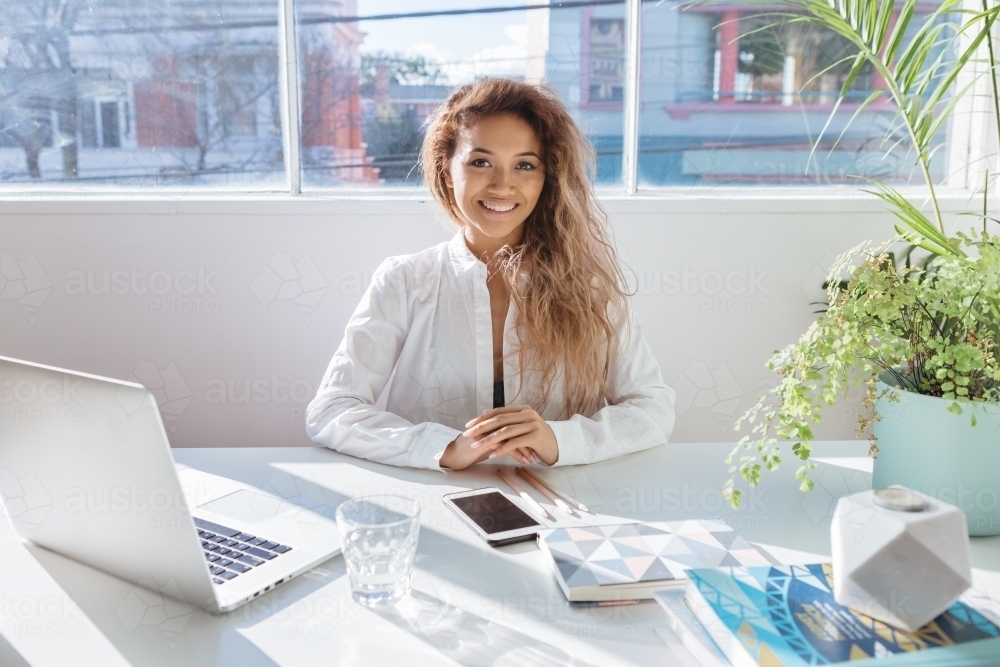 Happy employee posing for a business portrait at her desk - Australian Stock Image