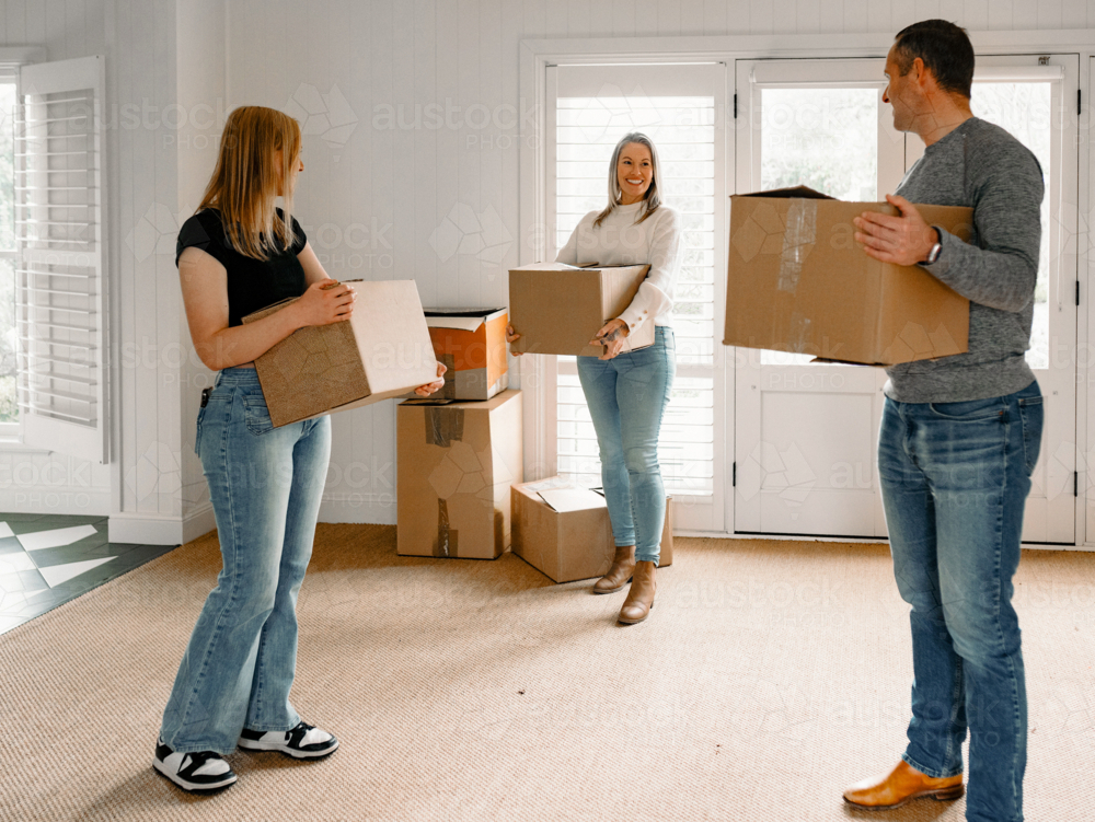 Happy family carrying boxes into their new home - Australian Stock Image