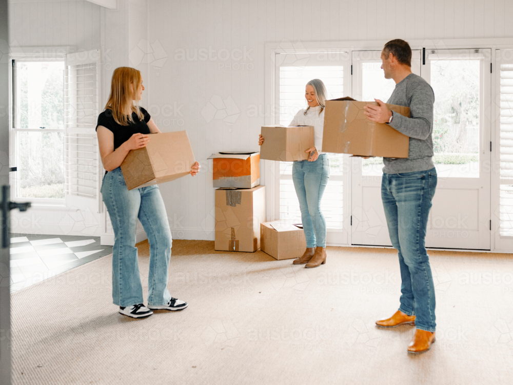 Happy family carrying boxes into their new home - Australian Stock Image