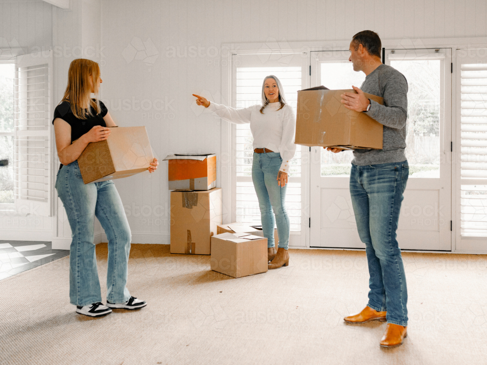 Happy family carrying boxes into their new home - Australian Stock Image