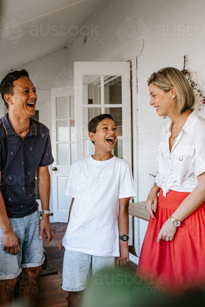 Happy family laughing together inside home - Australian Stock Image