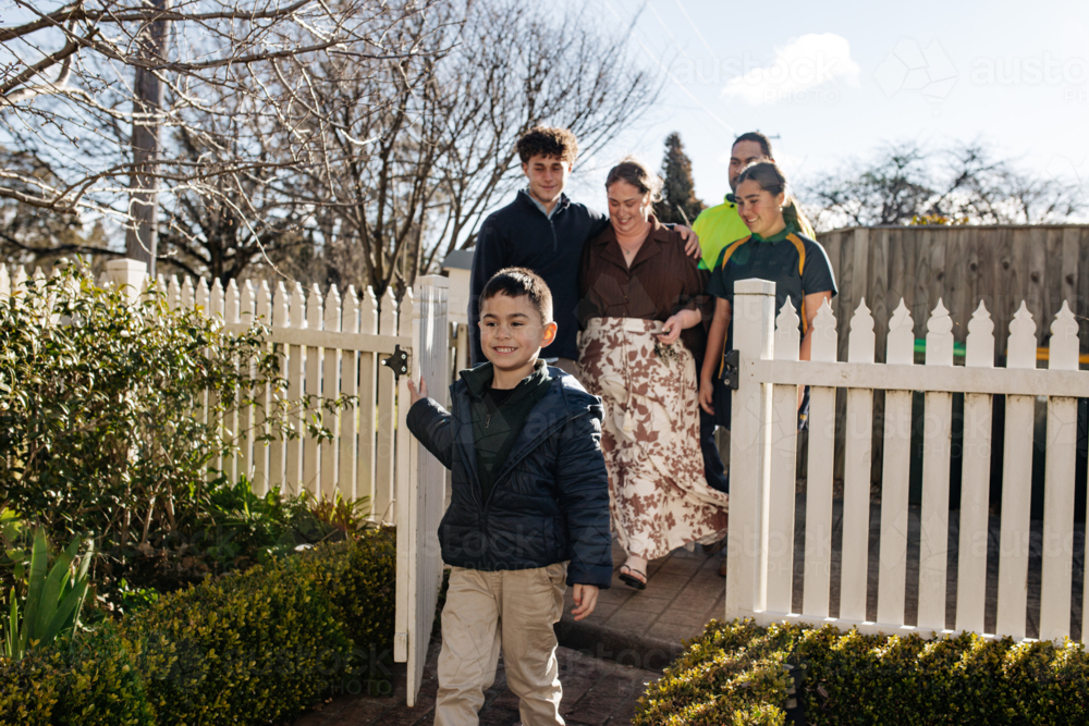 Happy family of mixed ethnicity walking into the yard with picket fence - Australian Stock Image