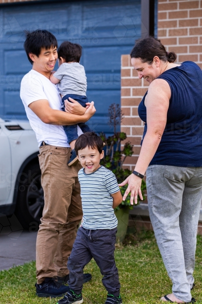Happy family smiling together outside home - Australian Stock Image