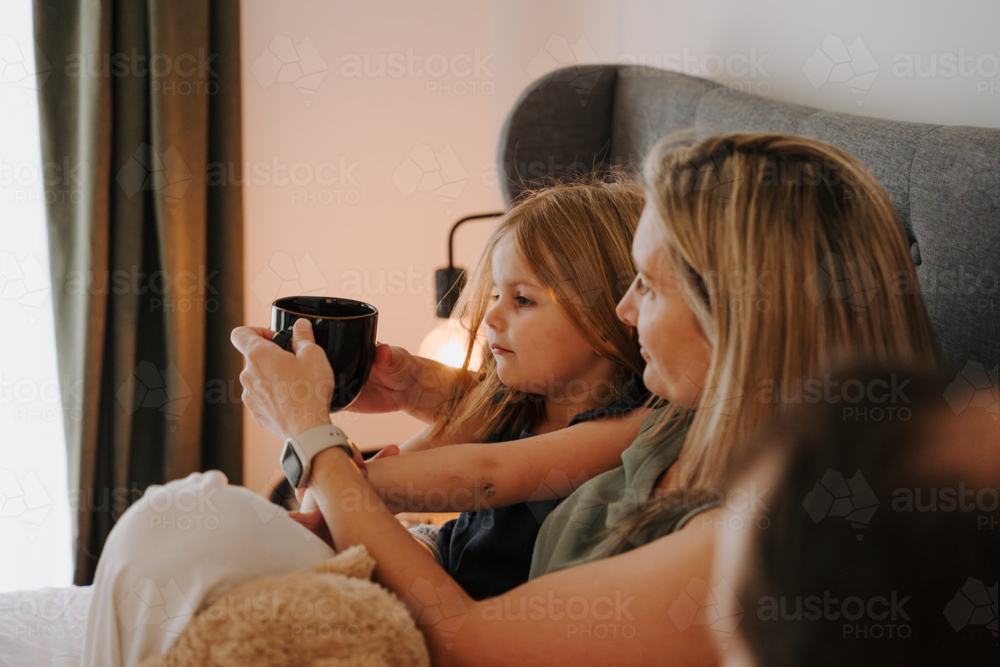 Happy family snuggling in a cosy bedroom. - Australian Stock Image