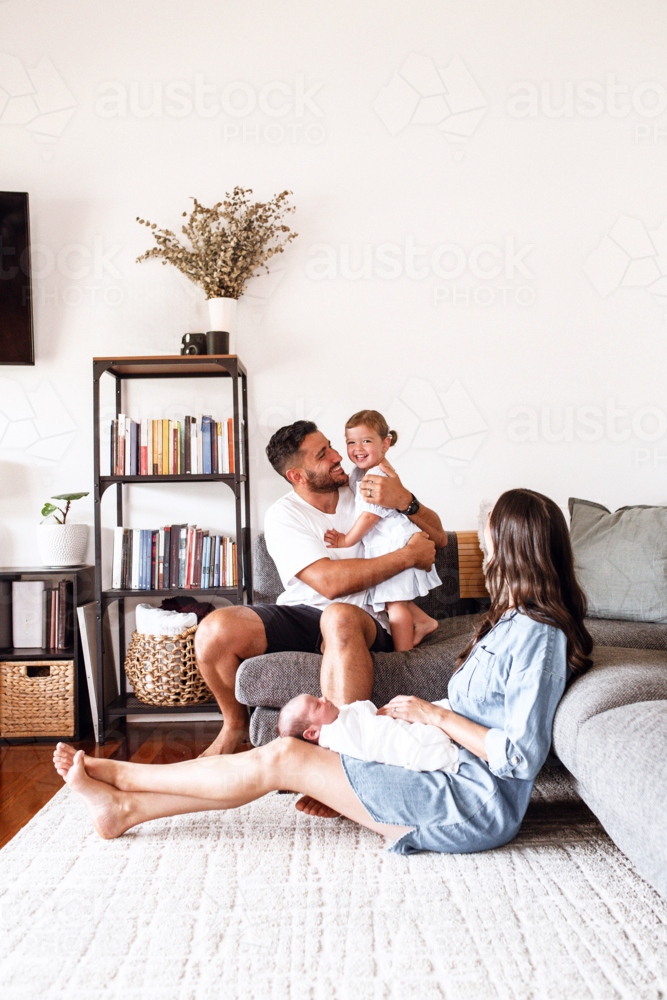 Happy family spending time together in the living room. - Australian Stock Image