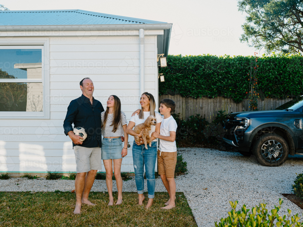 Happy family standing barefoot in their yard. - Australian Stock Image