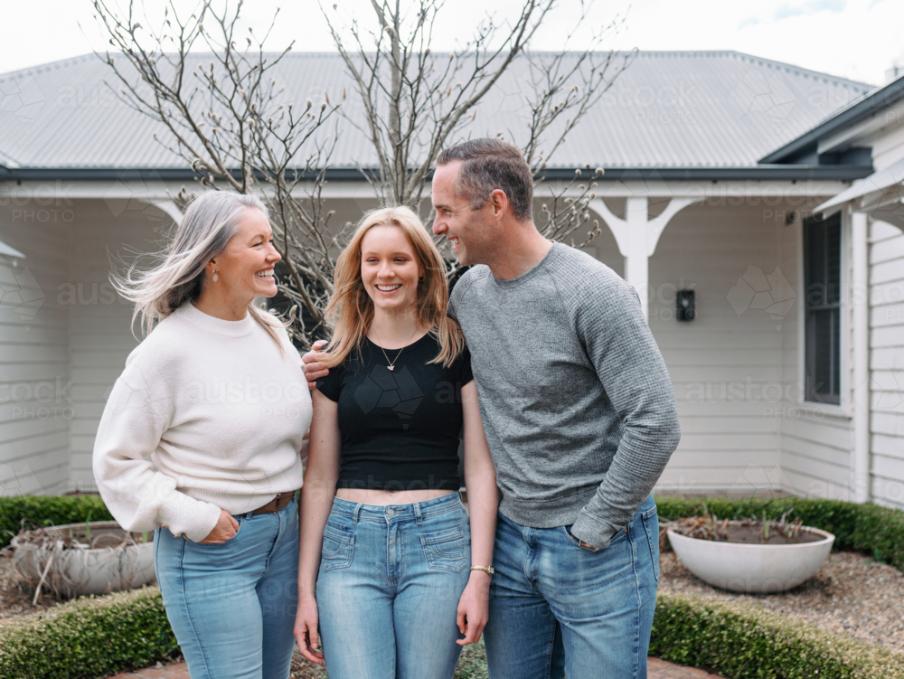 Happy family standing in the front yard of their new home - Australian Stock Image