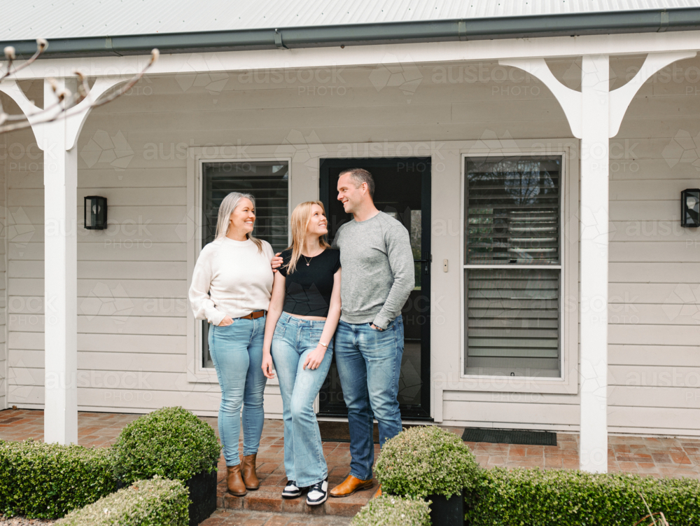 Happy family stands in the porch of their new home - Australian Stock Image