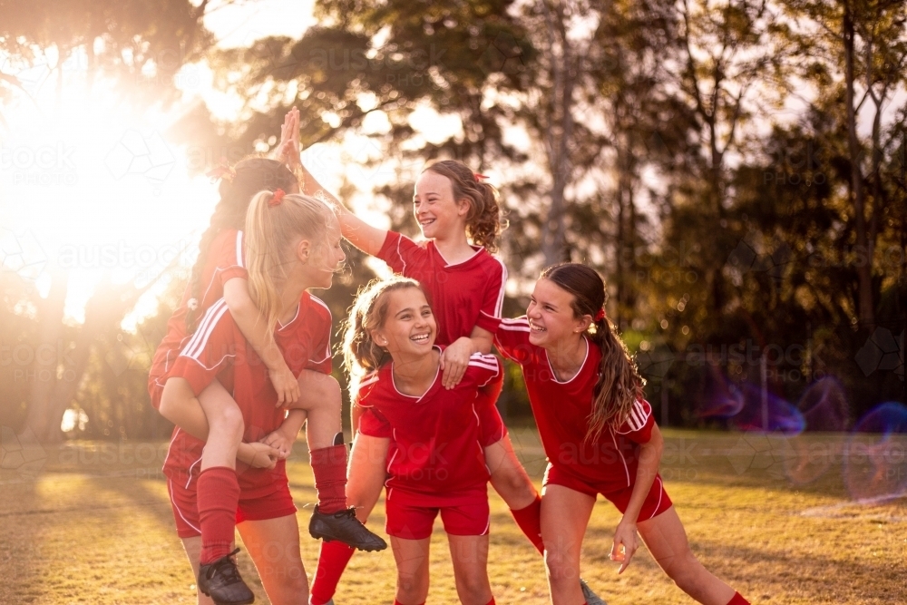 Happy football team of tween girls celebrating together - Australian Stock Image