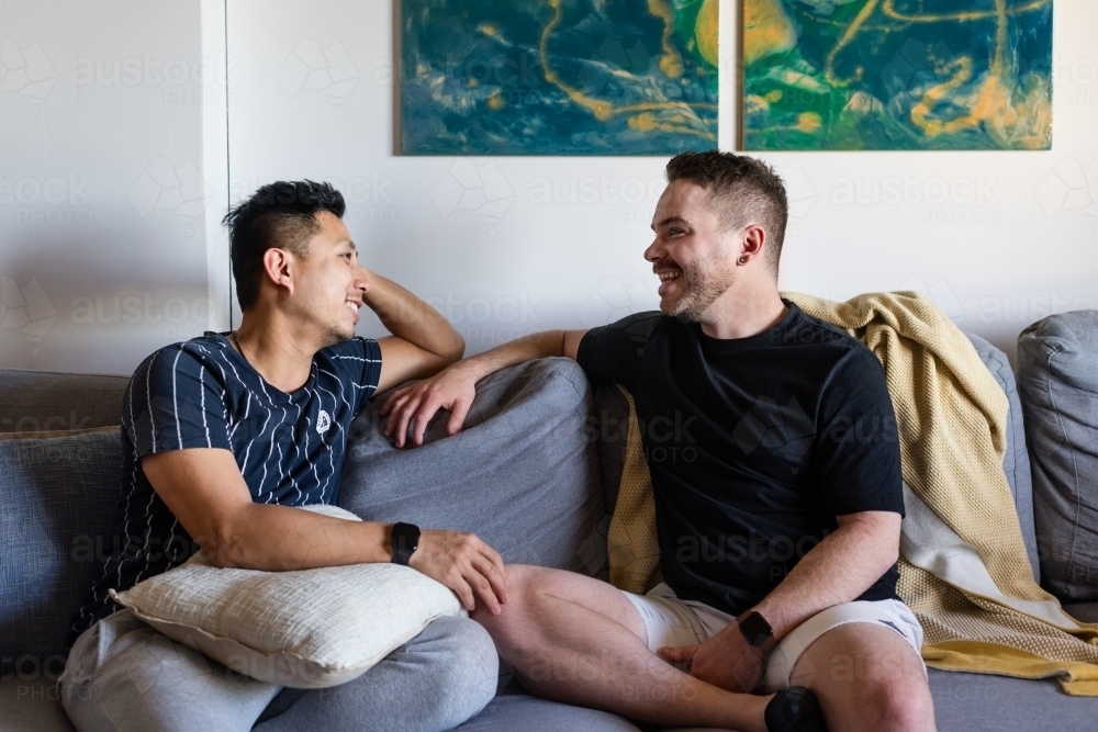 Happy gay couple on the sofa at home - Australian Stock Image