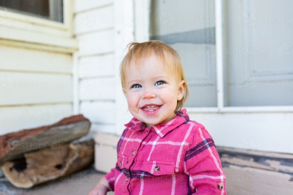 Image of Happy girl country kid portrait sitting on back doorstep of